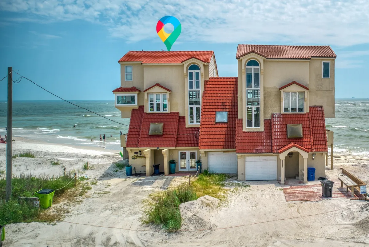 This exterior view presents the beachfront property with its inviting red-tiled roof set against the backdrop of the ocean and rolling sand dunes. The image evokes a sense of arrival and possibility for outdoor adventures, from beach walks to family gatherings by the water. The open sightlines and natural landscape reinforce the unique oceanfront setting.