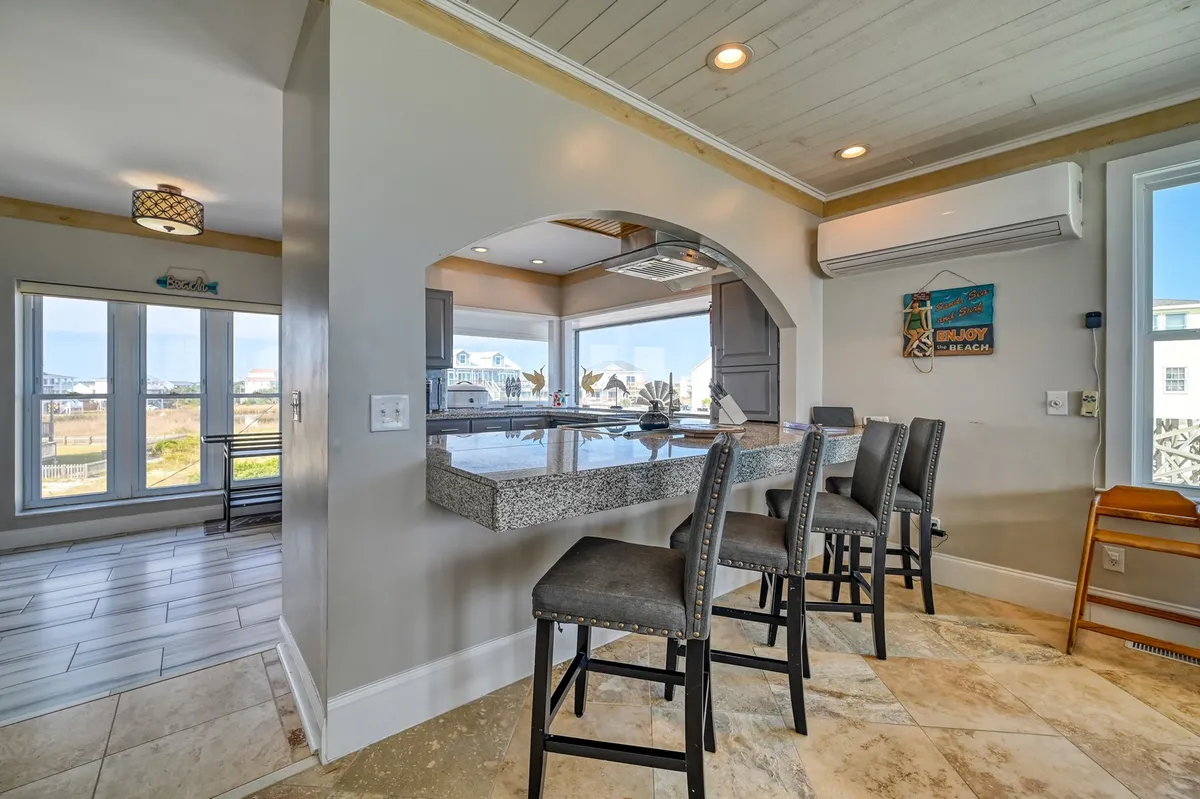 A kitchen bar with granite countertops, bar seating, and expansive windows overlooking the water. The setting is perfect for sunset drinks or casual meals after a day of exploring.