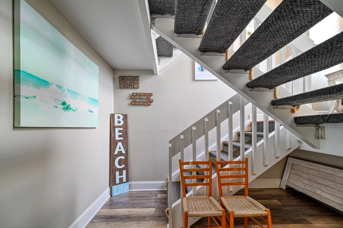 This interior image features a welcoming entry area with a beach-themed sign, ocean wave artwork, and wooden chairs, creating an inviting space for guests as they first arrive.